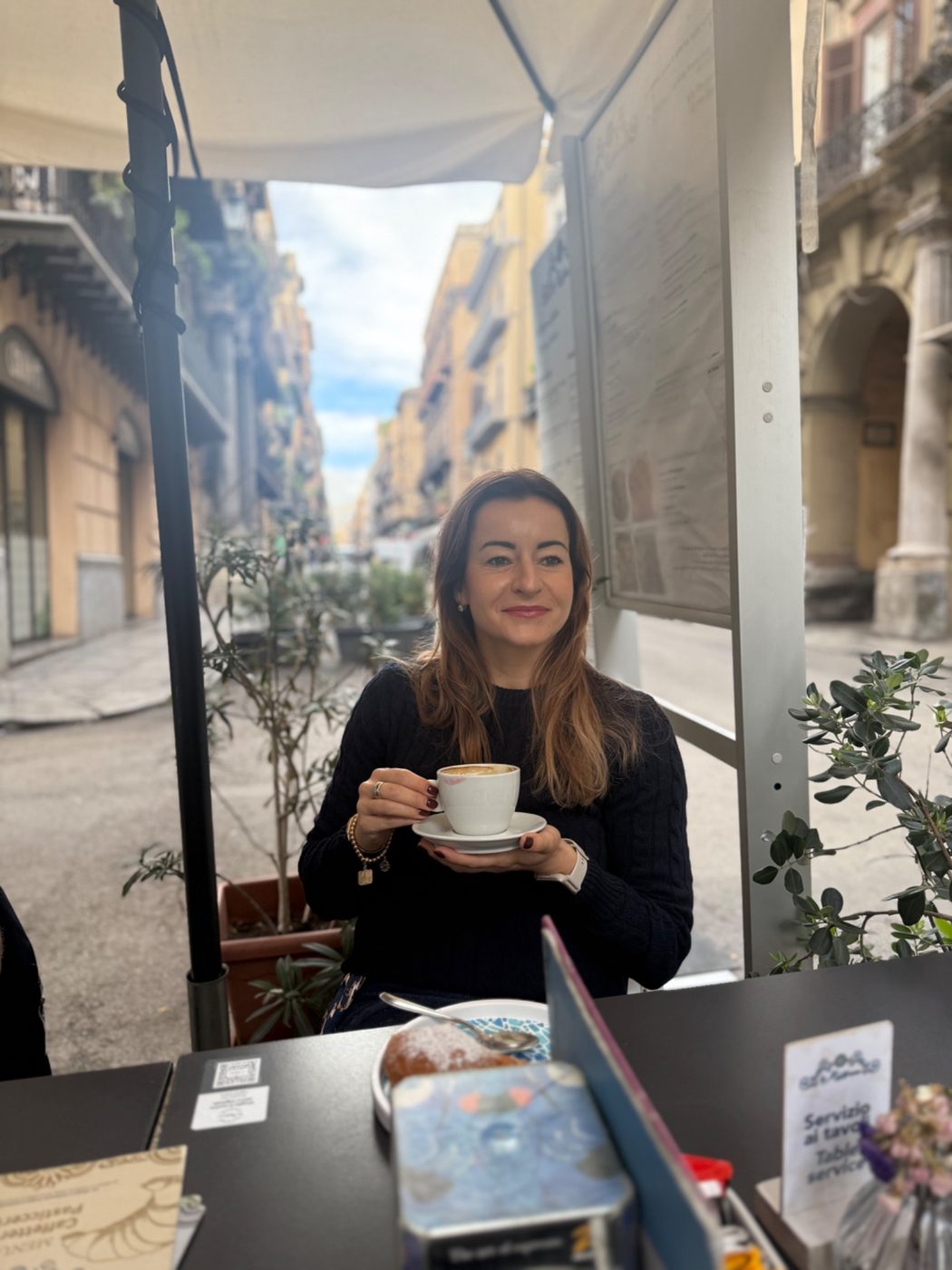 Magdalena Boreczek z filiżanką cappuccino w kawiarnianym ogródku na włoskiej ulicy