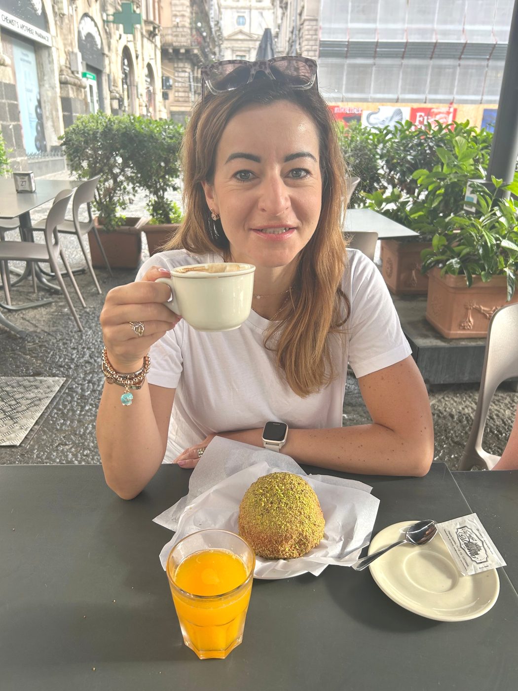 Magdalena Boreczek z filiżanką cappuccino przy stoliku w kawiarni na sycylijskiej ulicy